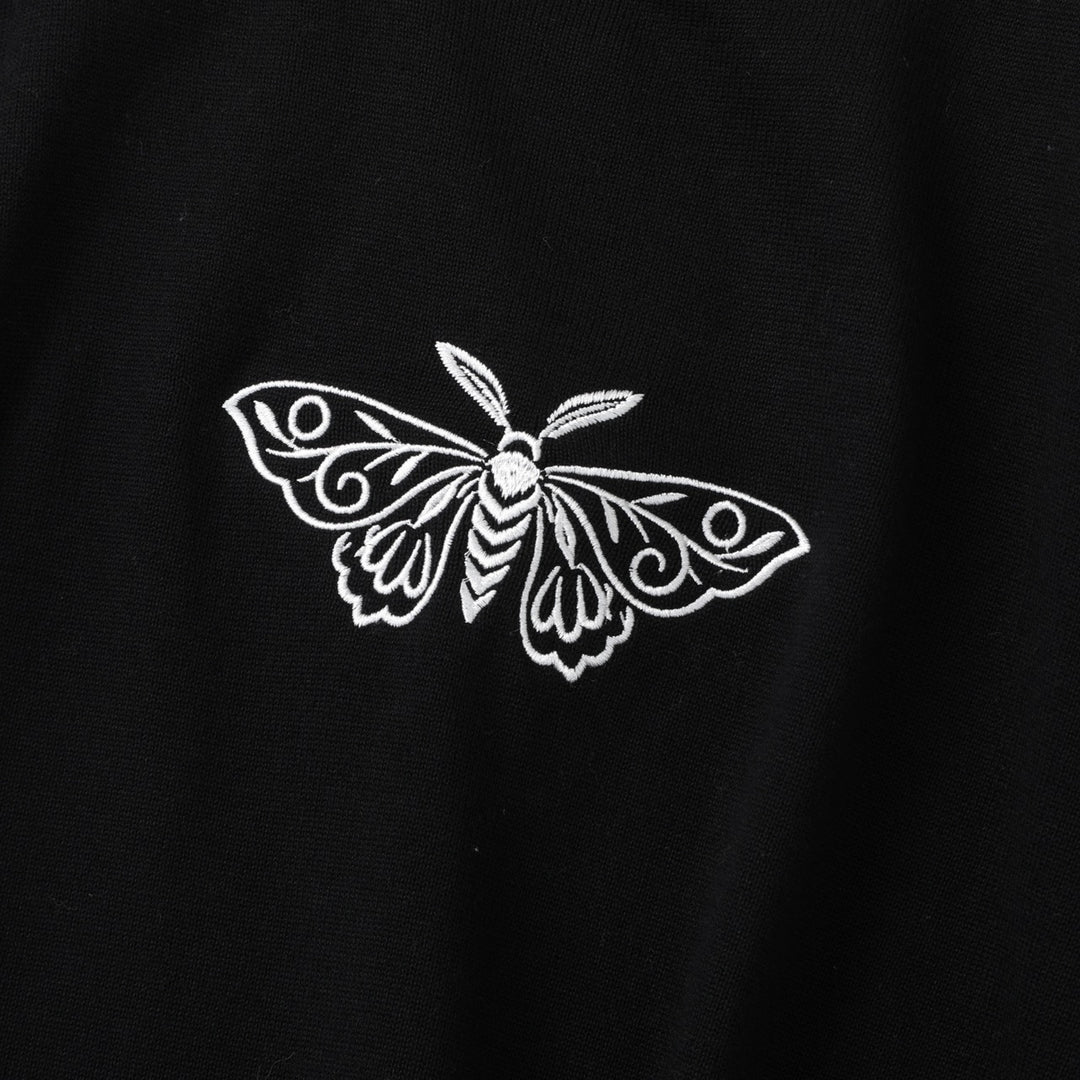 Damtröja i svart med polokrage, broderad mal och utsvängda ärmar