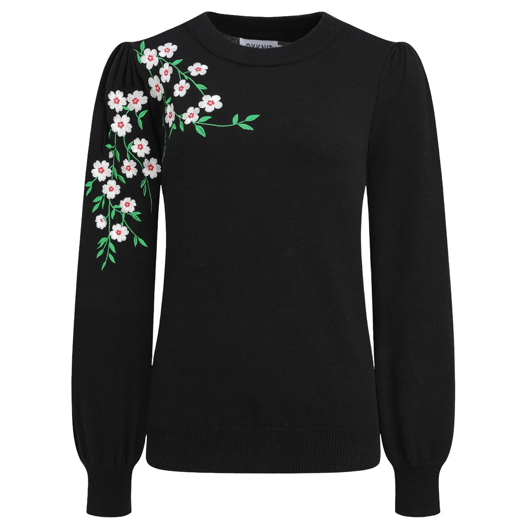 Women's black knit sweater with white floral embroidery and green leafy vines on the shoulder and sleeve, featuring a crew neck and long sleeves.